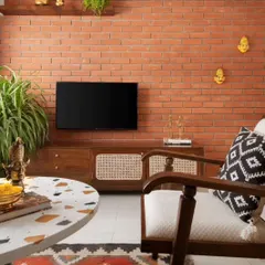 The living room's focal point is the exposed brick wall, which adds texture and warmth. The custom TV console with cane paneling continues the material theme, creating a cohesive look.