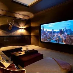We transformed this den into a cozy and inviting media room. The large screen is the centerpiece, complemented by a comfortable sectional sofa and warm, indirect lighting. This design proves that a compelling cinematic experience can be achieved in a relaxed, multi-purpose environment.