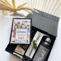 A modern and personalized onboarding kit. This hamper includes a custom-named bottle, a framed "Welcome to the Team" illustration, and other thoughtful items to welcome a new employee.