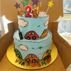 A trendy comic book style cake. This two-tier cake is designed to look like a cartoon drawing, with bold black outlines on the cars and clouds, creating a unique and eye-catching effect.