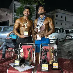 Two of my top athletes showing off their hard-earned trophies. You can see the muscle definition and conditioning that set them apart from the competition.