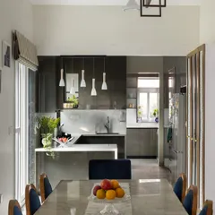 This open-plan kitchen and dining area is flooded with natural light. The dark grey, high-gloss cabinetry was chosen to complement the dramatic patterns in the floor tiles, while the white quartz countertop adds a clean, contrasting element.