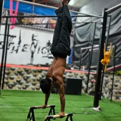 A clean handstand on parallettes, demonstrating core stability and shoulder strength. We build up to this with dedicated practice.
