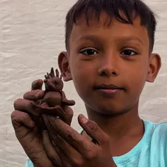 A young boy proudly presents his imaginative clay creature. Our community workshops are designed to be accessible and fun for everyone, regardless of age or experience.