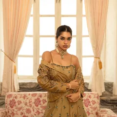 Using soft window light to create a gentle, romantic mood. This image highlights the delicate fabric and embroidery of the golden lehenga, showing how the outfit drapes and interacts with natural light.
