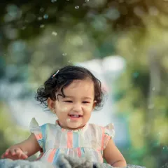 The simple joy of playing with bubbles. This candid shot captures a genuine smile and the magical atmosphere created by floating bubbles during an outdoor child portrait session.
