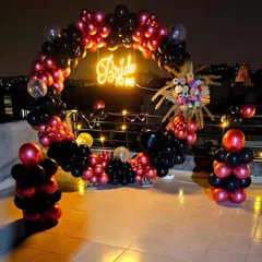 A clearer view of the rooftop "Bride to be" decor at night. The lighting highlights the rich colors of the balloons and the dried floral arrangement on the arch.