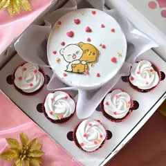 This cute hamper includes a truffle-flavoured bento cake with an illustration of two hugging bears. It is surrounded by six cupcakes with white frosting and tiny red hearts.