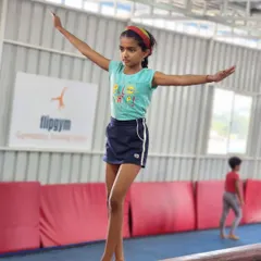 A student confidently walks across the balance beam, a fundamental skill for developing coordination and focus.