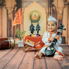 A playful shot with the baby holding a miniature veena. I use a variety of props in my cultural photoshoots to create diverse and engaging images.