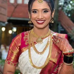 A beautiful smile from my gorgeous bride on her muhurtham. Her makeup features a classic bold red lip and subtly shimmering eyes, perfectly framed by her traditional gold jewelry and an elegant updo.
