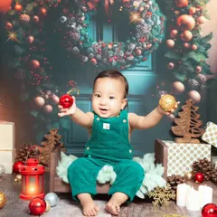 A vibrant and festive Christmas setup. This little one is ready for Santa with his green overalls and a backdrop full of holiday cheer.