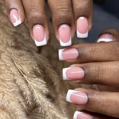 Another example of the classic French manicure, this time on a client with darker skin, showcasing its universal appeal. The crisp white tips and clean lines provide a polished and elegant look.