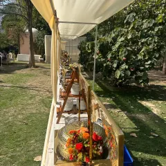 A side view of our outdoor buffet, showcasing the elegant arrangement of golden chafing dishes and floral centerpieces. We ensure every angle of our setup is picture-perfect.