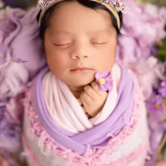 A close-up portrait focusing on the delicate features of a sleeping baby, crowned with a handmade floral headband. These macro-style shots are perfect for remembering just how tiny they were.
