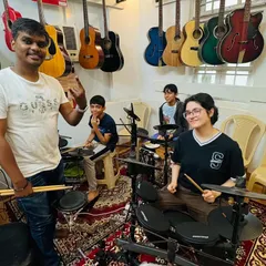 A drum coach with his students in our well-equipped studio. The walls are lined with guitars, creating an atmosphere that is immersive and inspiring for all musicians.