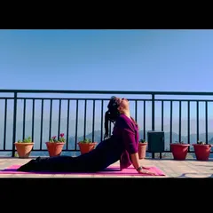 Demonstrating Bhujangasana (Cobra Pose) against a beautiful clear sky. This backbend is essential for spinal flexibility and strengthening the back muscles, especially during colder months.