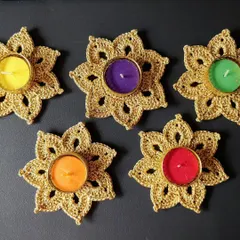 A top-down view of five golden tea light holders with colorful candles. They look stunning arranged together on a table.