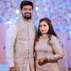 A formal portrait of a couple in stunning, coordinated embroidered outfits for their engagement ceremony.