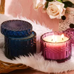 This shot creates a soft, pampering, and romantic mood for the candles. The fluffy white rug, pink background, and roses suggest a relaxing, self care experience, perfect for a bedroom or bathroom.