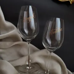 A set of personalized wine glasses for a couple, engraved with their names in a flowing script and the date on the base. These make for a beautiful and timeless wedding or anniversary gift.