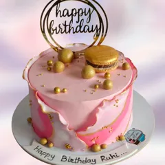 A beautiful fault line cake in shades of pink with elegant gold accents. Topped with golden spheres, a macaron, and a "Happy Birthday" topper, this design is perfect for a stylish celebration.