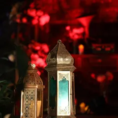 A pair of beautiful Moroccan lanterns cast a colorful glow, adding to the moody and romantic ambiance of an evening event.