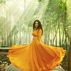 A full-length fashion shot of a model in a flowing orange lehenga, captured outdoors with beautiful natural light rays. This image demonstrates my ability to create dynamic, eye-catching visuals for ethnic wear and designer apparel brands.