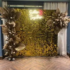 Our gold sequin shimmer wall makes a glamorous statement for any pre-wedding event. Paired with a custom "Better Together" neon sign and dried floral arrangements, it serves as a perfect photo backdrop for an engagement party or anniversary.