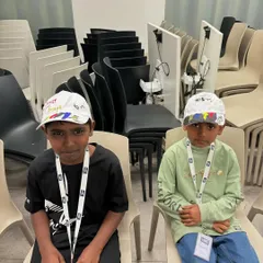 Two young boys sitting patiently after finishing their cap painting. It's wonderful to see them so proud of their work.