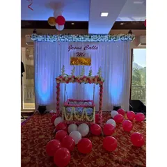 A beautiful cradle decoration for a naming ceremony. The 'palna' is adorned with pink and white flowers, set against an elegant backdrop of white curtains and soft lighting, creating a divine look.