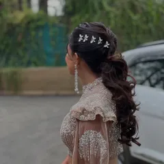 A detailed shot of the bride's chic Sangeet hairstyle. A voluminous ponytail adorned with delicate butterfly clips, perfect for a night of dancing.