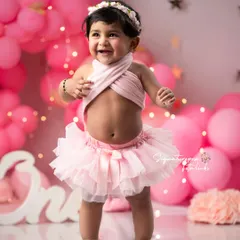 Standing tall and proud on her first birthday. This portrait captures a key milestone, the ability to stand, amidst the fun and festive setup of her cake smash session.