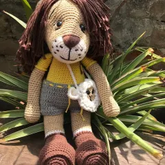 Jireh the lion sitting amongst the plants. He's a large and huggable doll, perfect for storytelling and imaginative play.