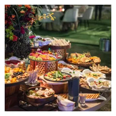 A wide shot of a beautiful outdoor grazing table, laden with Mediterranean and Middle Eastern dips, salads, and breads. This setup is perfect for a relaxed yet sophisticated garden party or sundowner.