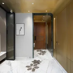 The entryway of this New Delhi residence sets a tone of refined elegance. The design features warm brass paneling, a concealed door for a seamless look, and custom marble flooring with geometric inlays. An arched pooja alcove is integrated into the design, blending spiritual serenity with modern aesthetics.