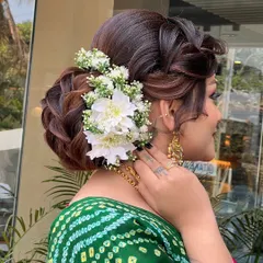 A side profile of the floral bridal bun, showing the detailed braiding and how the fresh flowers are integrated into the hairstyle for a seamless look.