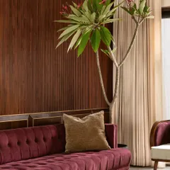 A detail shot showing the deep tufting on the plum velvet sofa, set against a rich wood-paneled wall. This image emphasizes our focus on texture and craftsmanship, even within a bold, maximalist design.