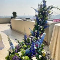 This cascading installation on a rooftop terrace was designed to feel like a waterfall of flowers. The blend of blues and greens against the city skyline creates a stunning contrast, proving that bold floral art can thrive in any environment.