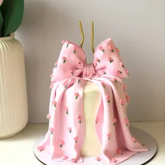 A chic and fashionable bow cake. The buttercream is draped and folded to look like fabric, with tiny hand-piped flowers for a delicate finish.