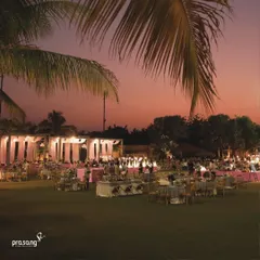 An overview of an outdoor reception at dusk. The warm lighting, elegant seating, and lush green lawn create a magical and romantic atmosphere for an evening of celebration.
