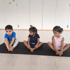 Young children practice a butterfly stretch on their mats, improving flexibility in a fun, group setting.