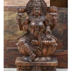 A 30-inch wooden sculpture of Goddess Maha Lakshmi, the embodiment of prosperity and grace. Seated on a lotus and holding lotus buds, her hand is raised in the gesture of blessing.