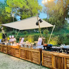 This rustic wooden buffet station was designed for an elegant outdoor event. The clean lines, professional chef service, and clear signage for each food station ensure a sophisticated and organized dining experience for all guests.