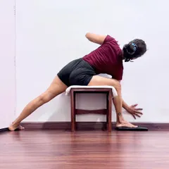A supported variation of Parivritta Trikonasana (Revolved Triangle Pose) using a stool. The support ensures the foundation of the pose is stable, which is essential for the brain to float and for the practitioner to develop a positive, steady attitude.