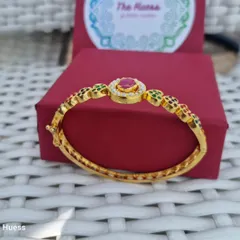 A full view of the "Ada" bracelet, showing its beautiful symmetry and the central ruby-toned stone. It's an openable bracelet, making it easy to wear.