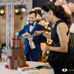 Another angle of this happy couple enjoying their wedding cake moment. The rich, multi-tiered chocolate and berry cake stands as a beautiful centerpiece for their celebration.