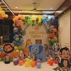 A colorful jungle theme party for Ameerah's first birthday. This decoration is packed with friendly animal cutouts like a lion, elephant, and monkey, set against a vibrant rainbow balloon arch.