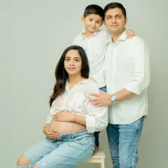 A classic family portrait with everyone dressed in coordinated white shirts and jeans. This clean, modern look keeps the focus on the family's connection and the beautiful baby bump.