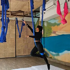 A graceful pose captured during my aerial yoga teacher training. The silk provides support, allowing for deeper stretches and movements that might not be accessible on the mat, making it ideal for injury recovery and building confidence.